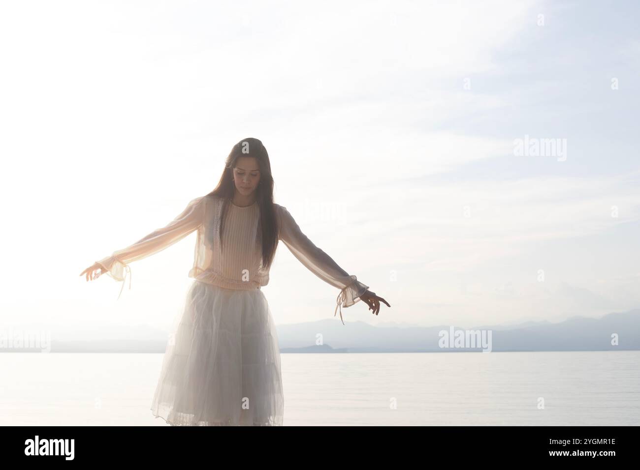 woman balancing on the rocks walking with her back to a spectacular view of the sea, concept of freedom Stock Photo