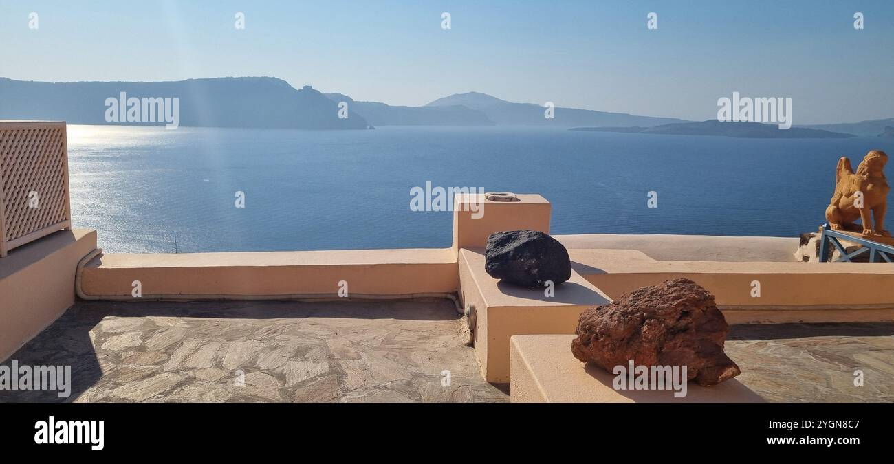 Stunning view of the sea in Santorini, from a balcony decorated with beautiful stones and statues. - Smartphone Captured Stock Image