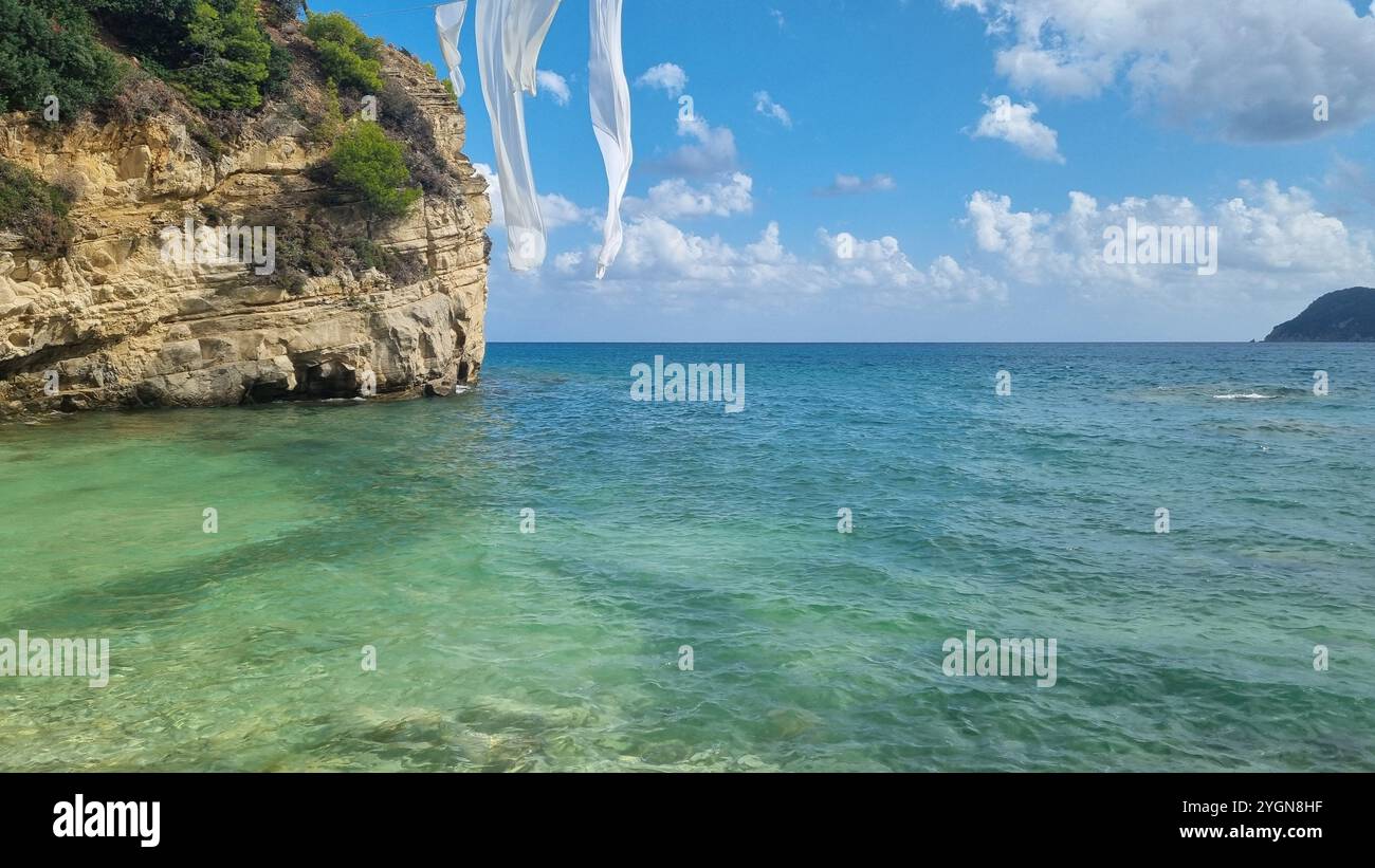 Pleasant view of the blue sea on a sunny day, with white fabric floating in the wind. - Smartphone Captured Stock Image