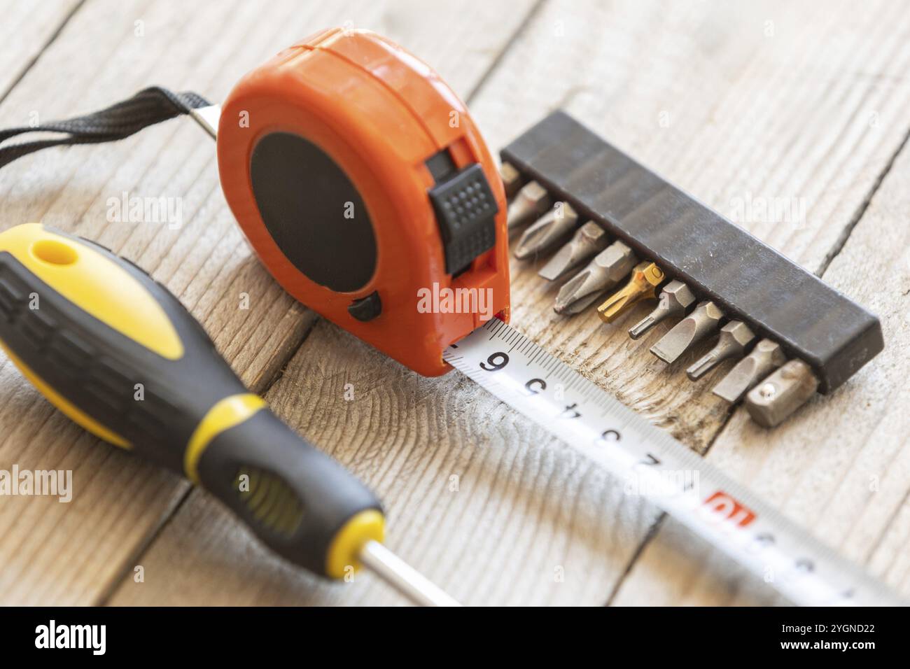 Measuring Tape Tool and screwdriver bits set on wooden background Stock Photo