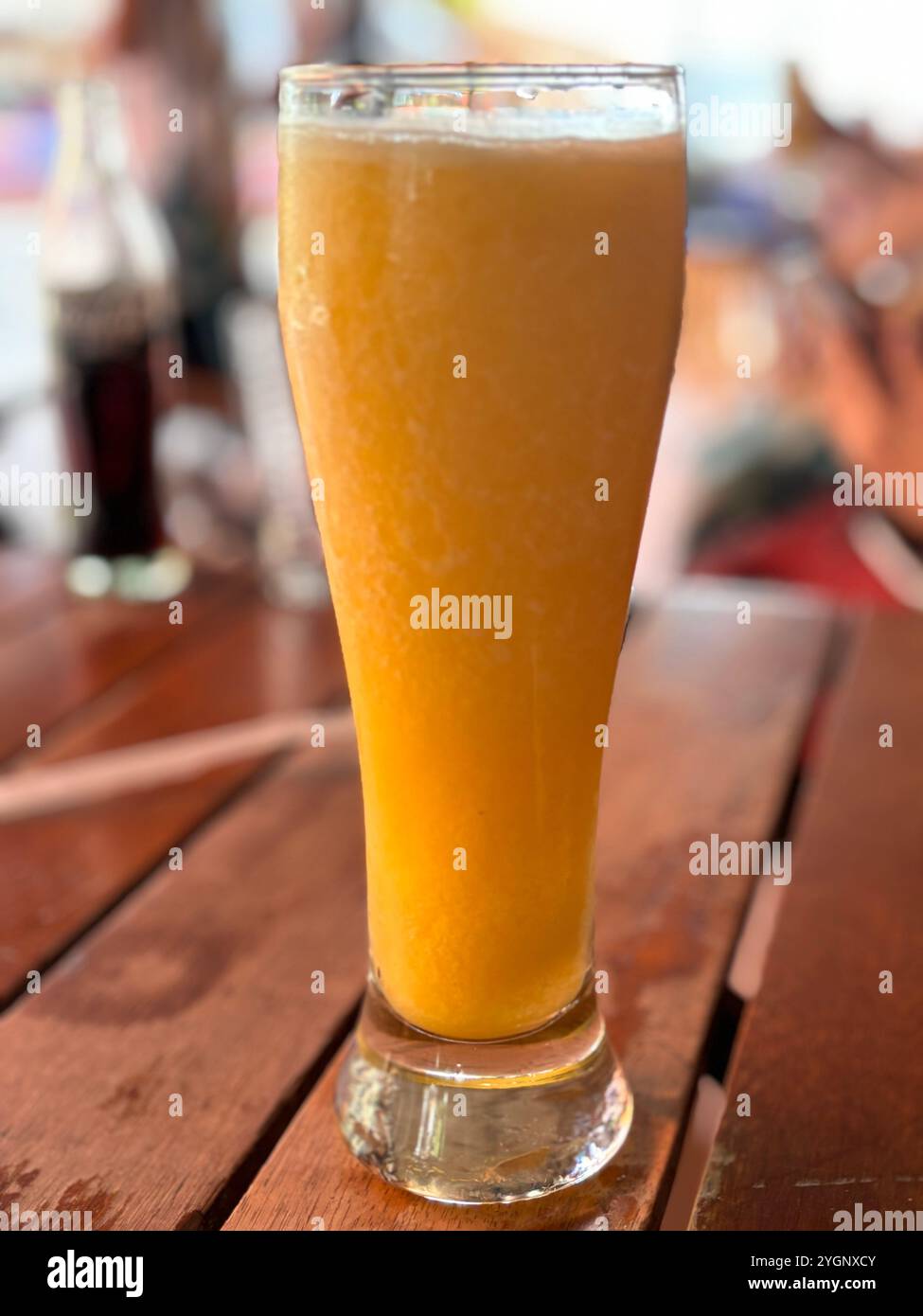 A tall glass of fresh orange juice on a wooden table, capturing the essence of a refreshing and healthy drink, perfect for a warm day. - Smartphone Captured Stock Image