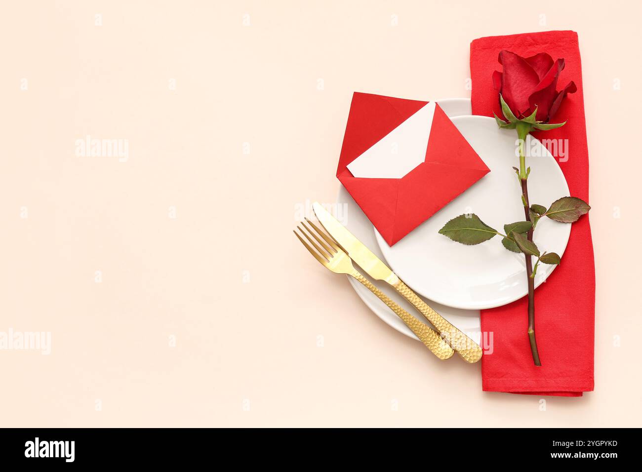 Beautiful table setting with red rose and envelope on beige background ...