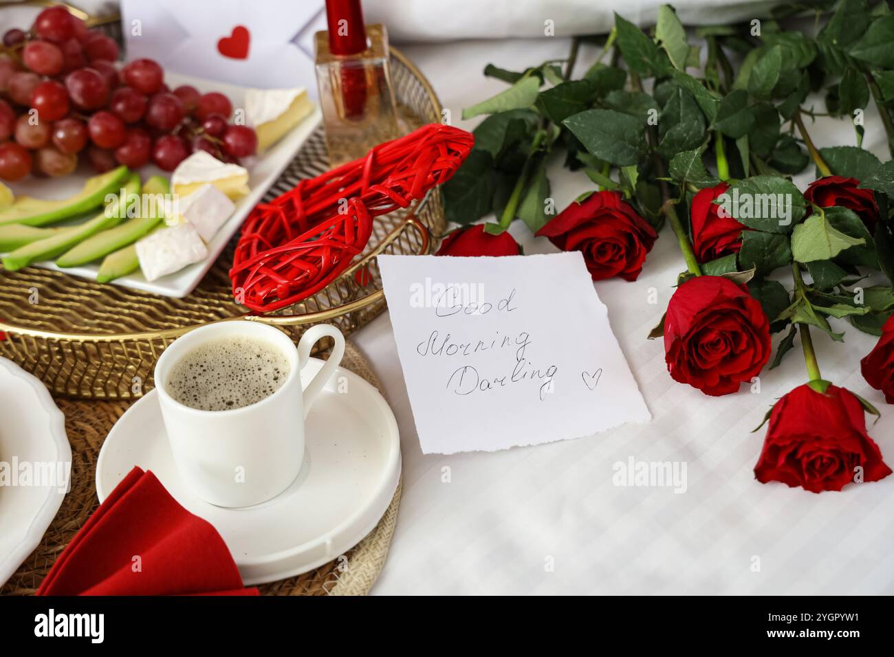 Tasty breakfast for Valentine's Day with paper note on bed, closeup ...