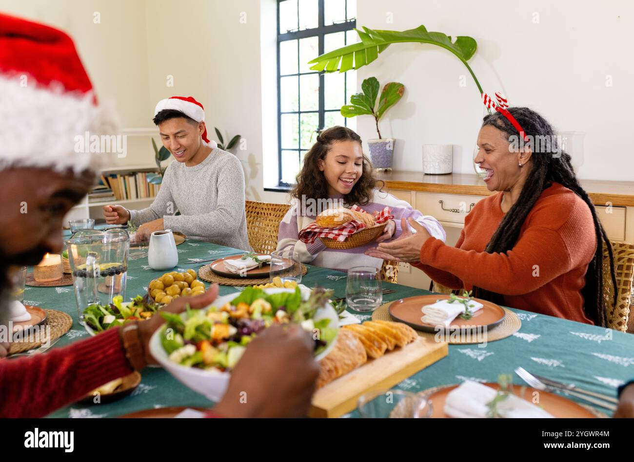 multiracial family celebrating Christmas, sharing food and laughter at festive dinner table, at home Stock Photo