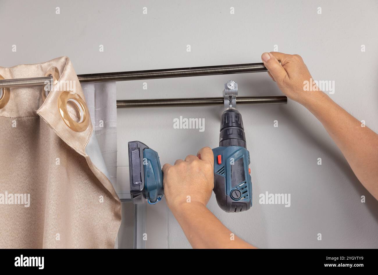 Worker repairman hanging and fixing the curtain on the window Stock Photo