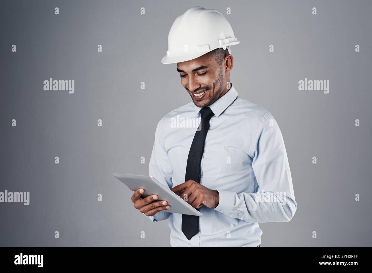 Engineer, tablet and happy with digital research and online blueprint of builder in studio. Contractor, planning and helmet of Indian male Stock Photo