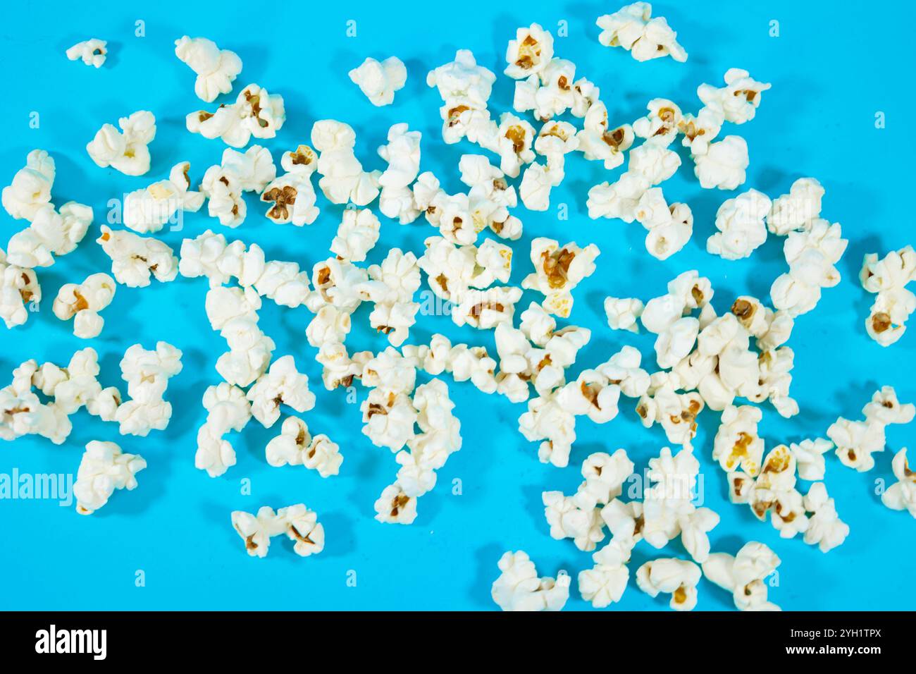 Top view of scattered popcorn on a blue background, cinema food concept Stock Photo
