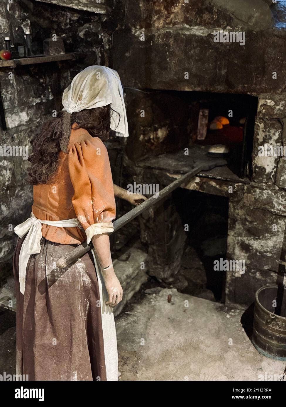 'A traditional kitchen scene with a woman baking bread in an old oven, capturing a nostalgic glimpse into the past.' - Smartphone Captured Stock Image