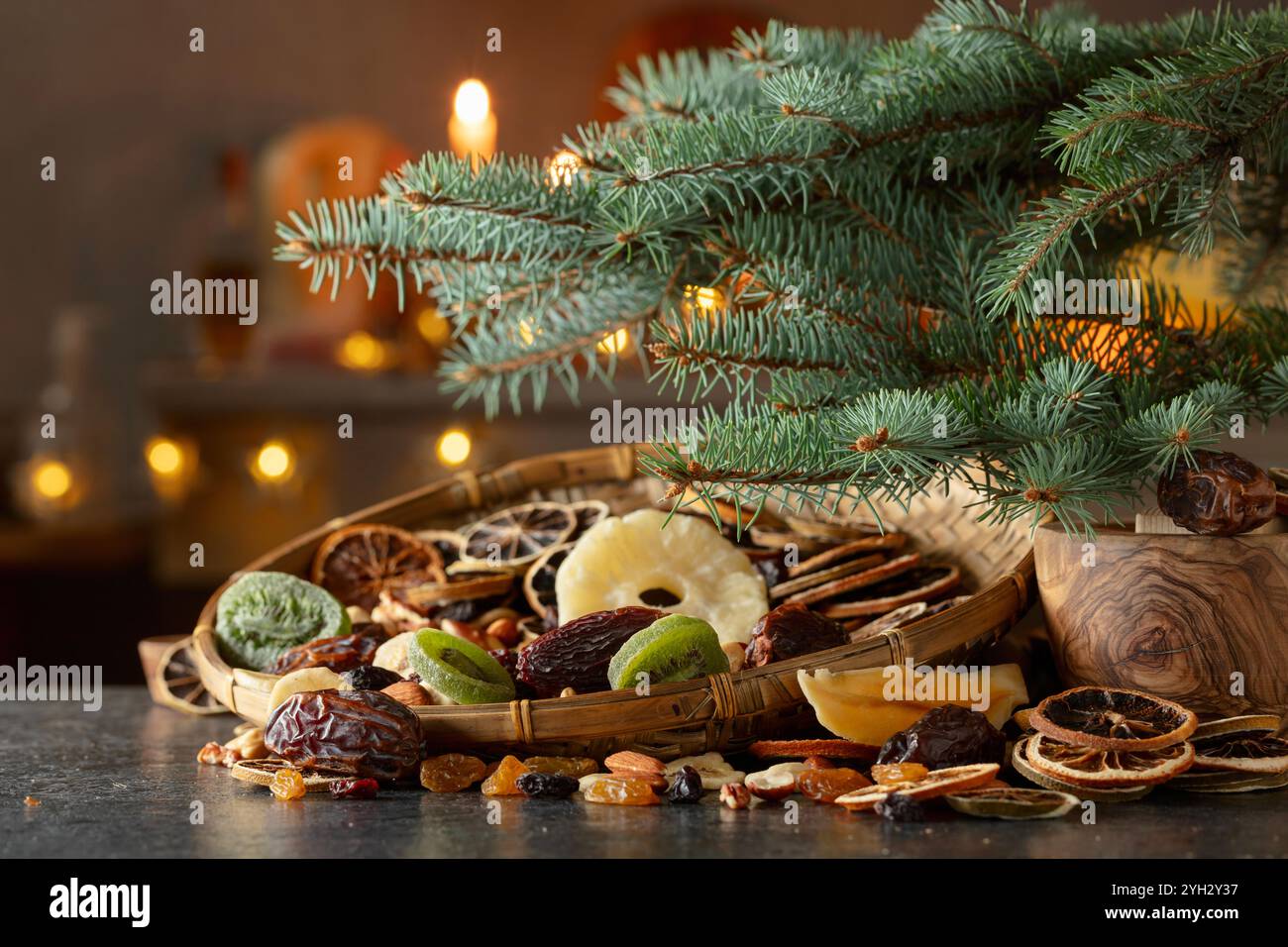 Dried tropical fruits with various nuts and raisins. Sweet tropical fruits and Christmas tree on a kitchen table. Stock Photo