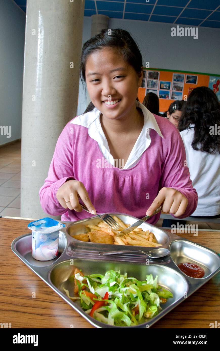 Teenage Korean girl school student smiling attractive 15-17 years at table having formal healthy balanced lunch school dinner in senior school canteen Stock Photo