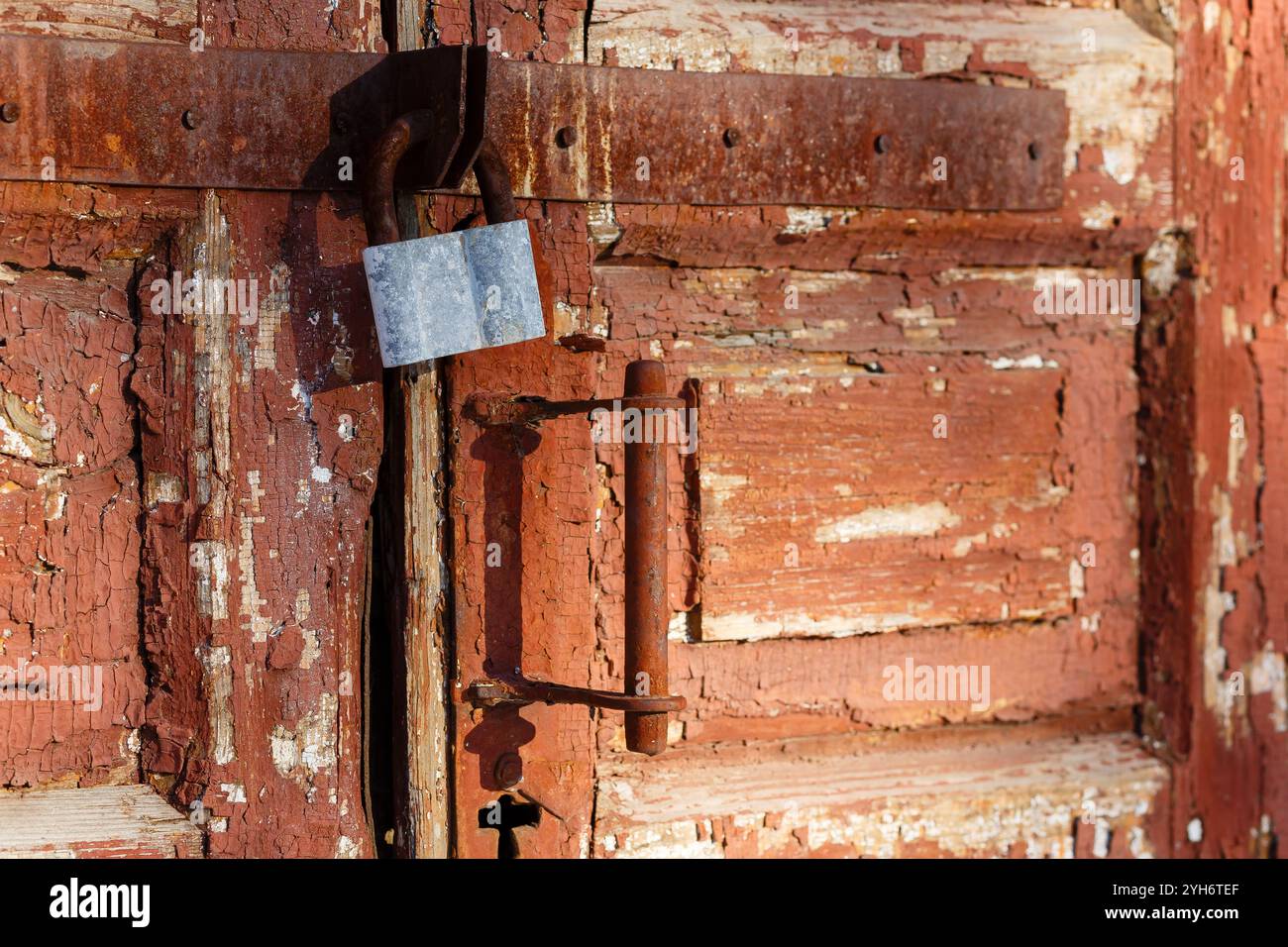 Old traditional wooden door with rusty metal lock close-up. Metal lock for security. Lock on the door. Close-up of a wooden door with a handle and a l Stock Photo