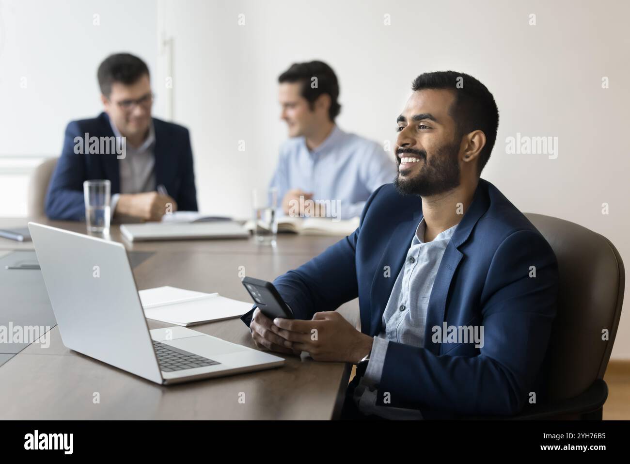 Successful dreamy young Indian office professional man using digital devices Stock Photo