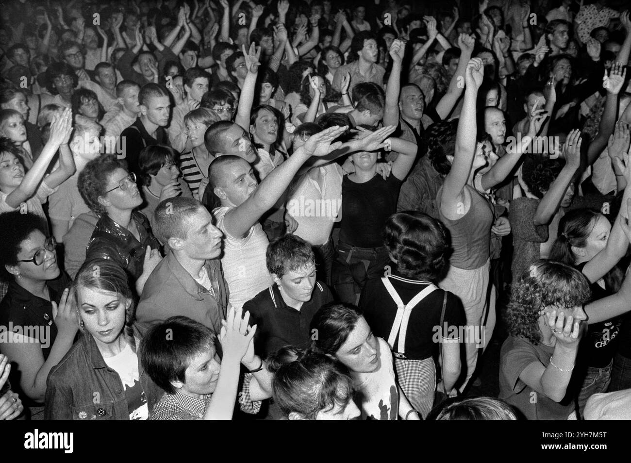 Skinheads and young people, clubbing at The Electric Ballroom, dancing to UB40 band. Jimmy John, skinhead (centre middle) giving the Nazi salute along with a skinhead friend. They were what was then called 'Sieg Heiling' a common 'salute' by skinheads of the time. Camden Town, London, England 1980 1980s UK HOMER SYKES Stock Photo