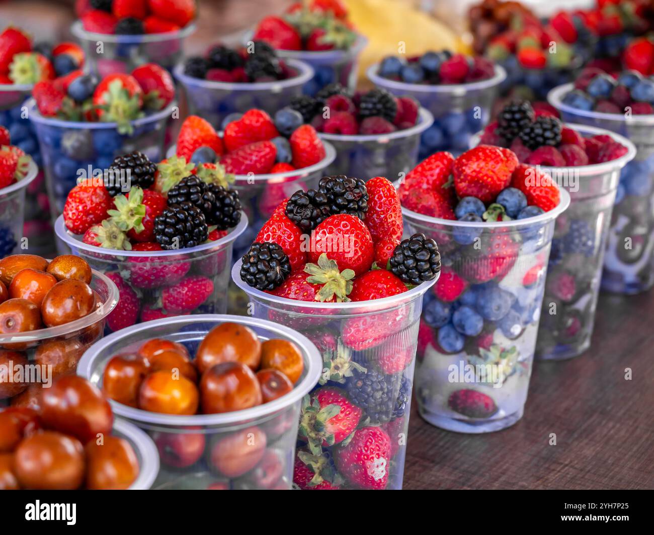 Close-up colorful mixed berry fruit Cups, red strawberries, blueberries, mulberry sale food in plastic cups in Georgia. Stock Photo