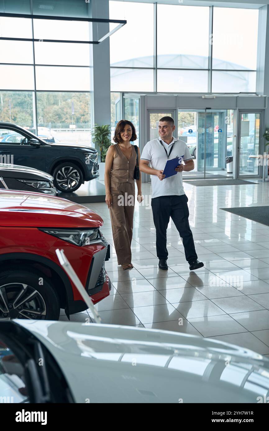 Salesman manager with file folder and female customer standing in car ...