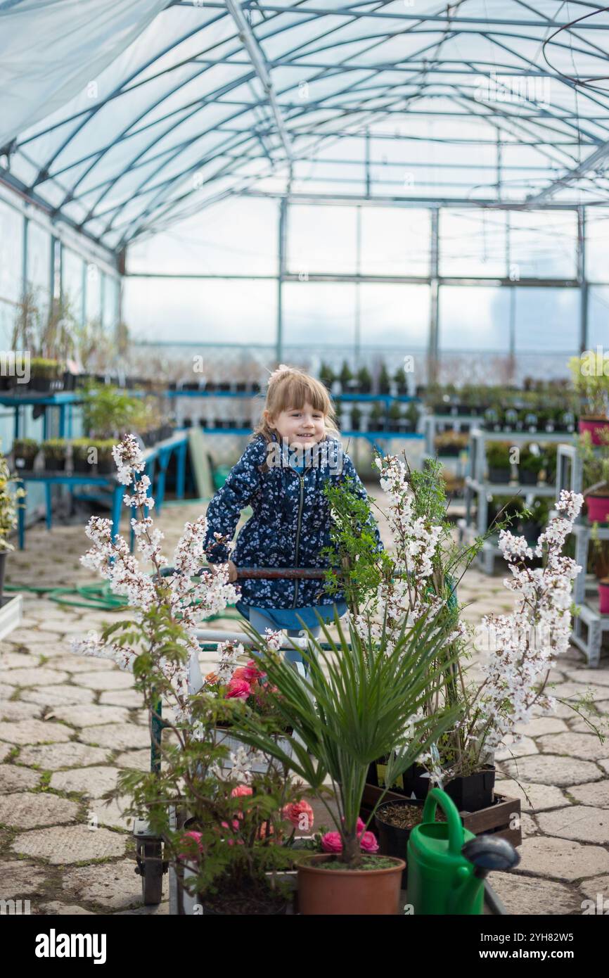 Young Girl sitting in a Shopping Cart in Greenhouse Gardening Center ...