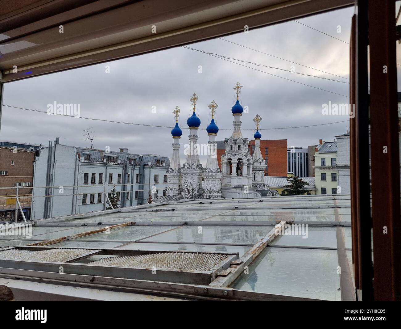 View through window on Orthodox church with blue cupolas with crosses on white church towers (Nativity Church at Putinki) in Moscow, Russia - Smartphone Captured Stock Image