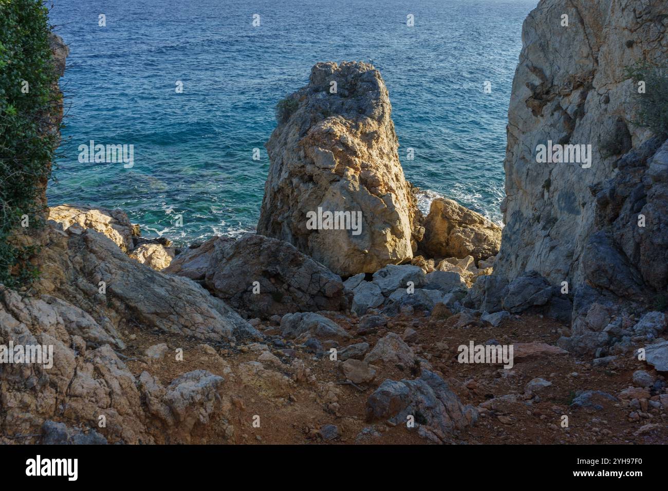 Gentle waves meet rugged rocks as the sun rises, creating a serene ...
