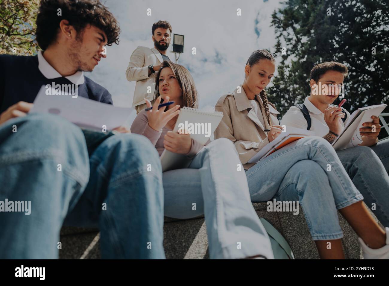High school students collaborating outdoors with professor's guidance Stock Photo