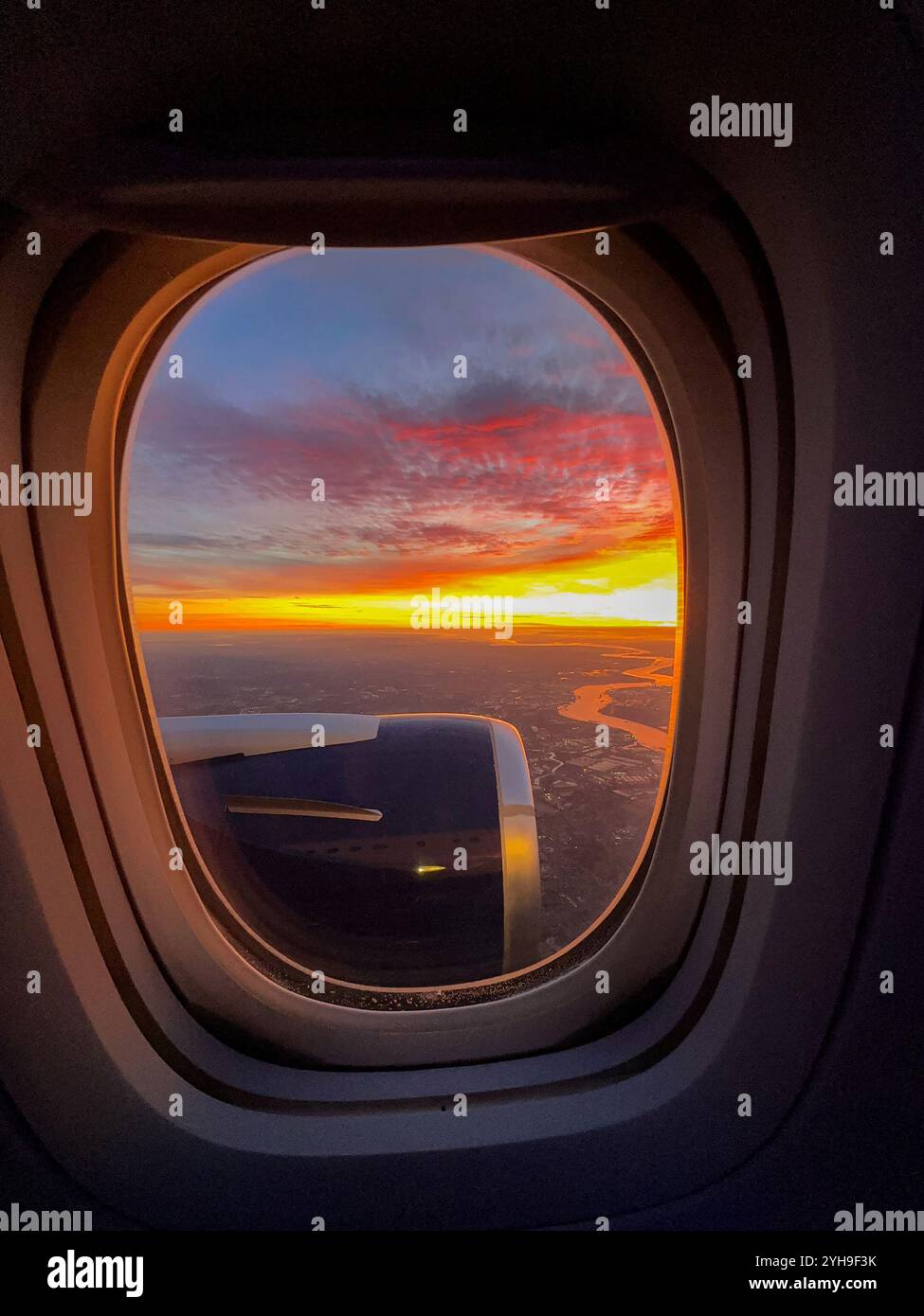 Sunrise over the horizon seen through the window of a holiday jet - Smartphone Captured Stock Image
