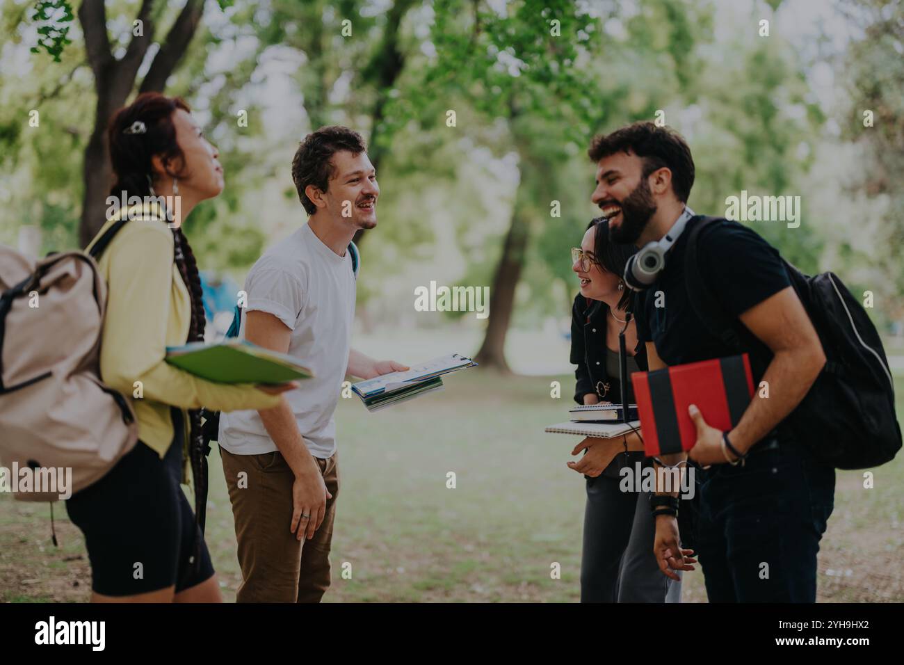 Multicultural students collaborating on projects in a sunny park setting Stock Photo