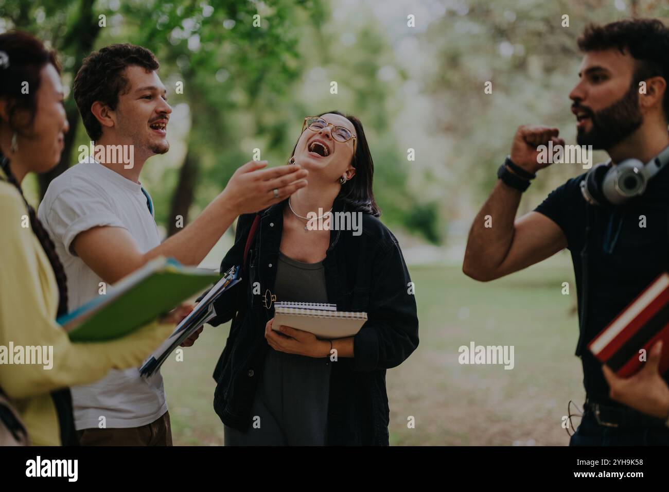 Multicultural students collaborating on assignments in the park after class Stock Photo