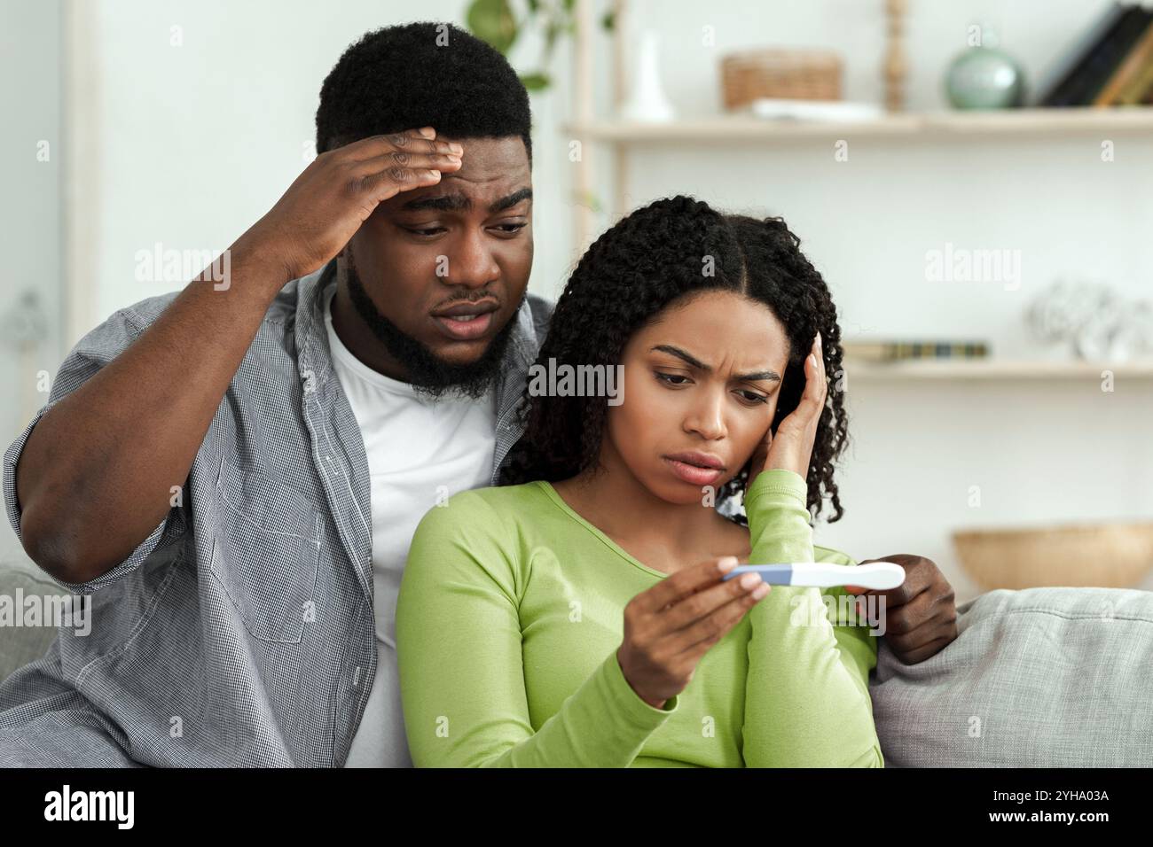 Unintended pregnancy. Concerned african american couple upset with positive test results Stock Photo