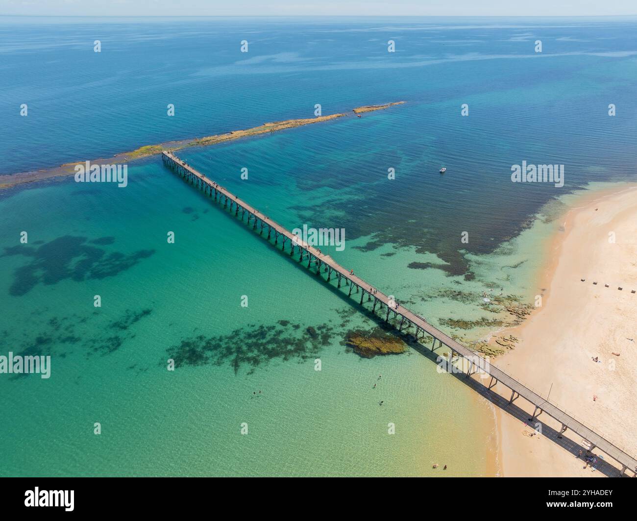 Aerial view of a long coastal jetty going out to a rocky reef in a shallow bay at Port Noarlunga in South Australia Stock Photo