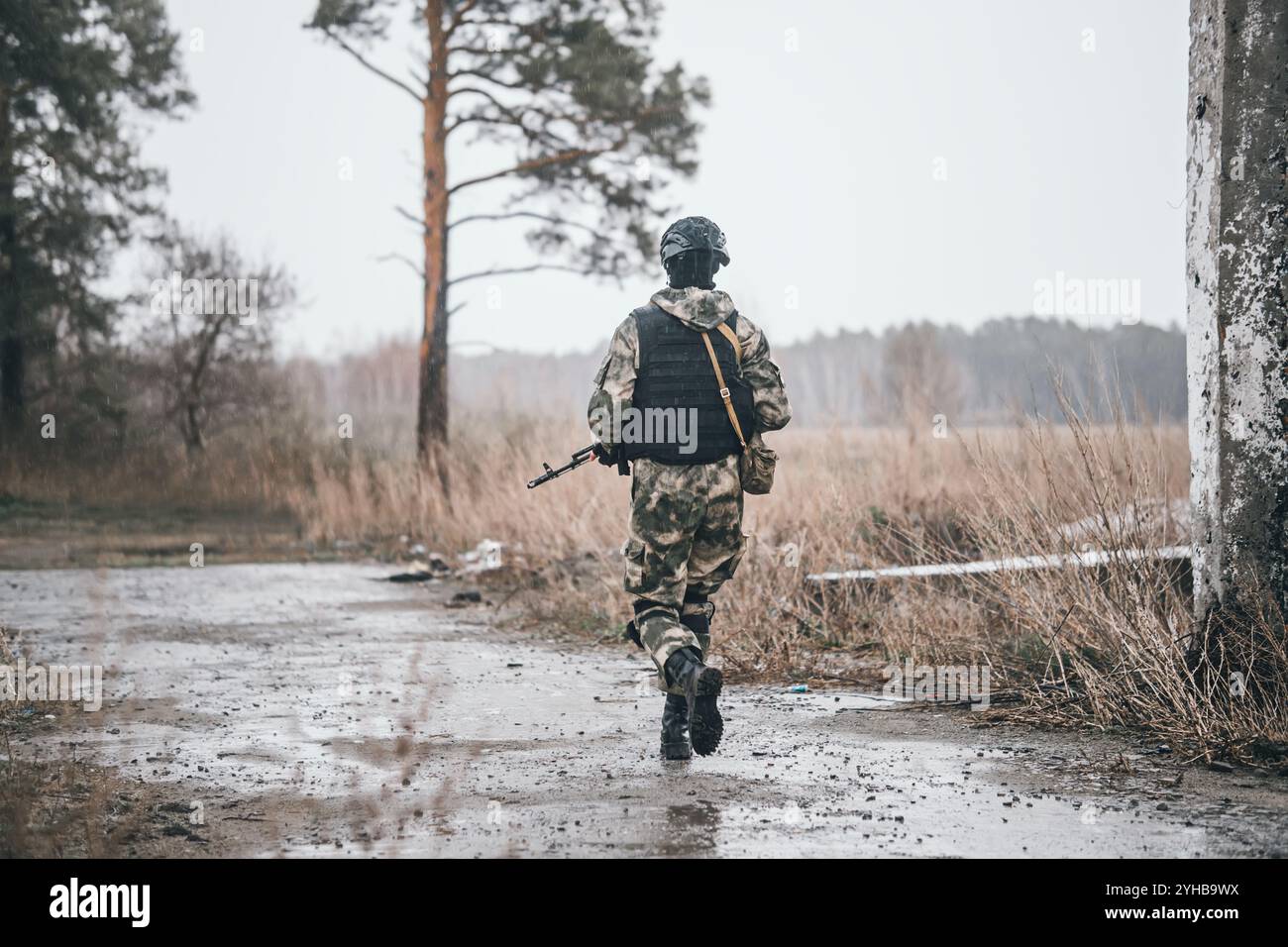 Soldier or militiaman in camouflage with assault rifle fighting in ruins. A special forces soldier in uniform walks against the background of a destro Stock Photo