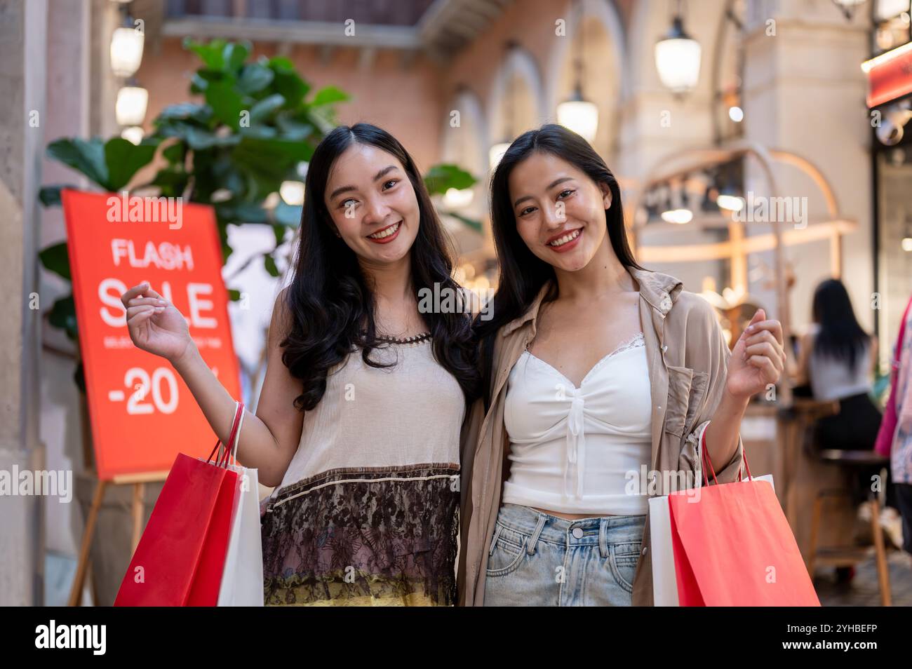 A portrait of two attractive Asian women standing in a shopping mall ...