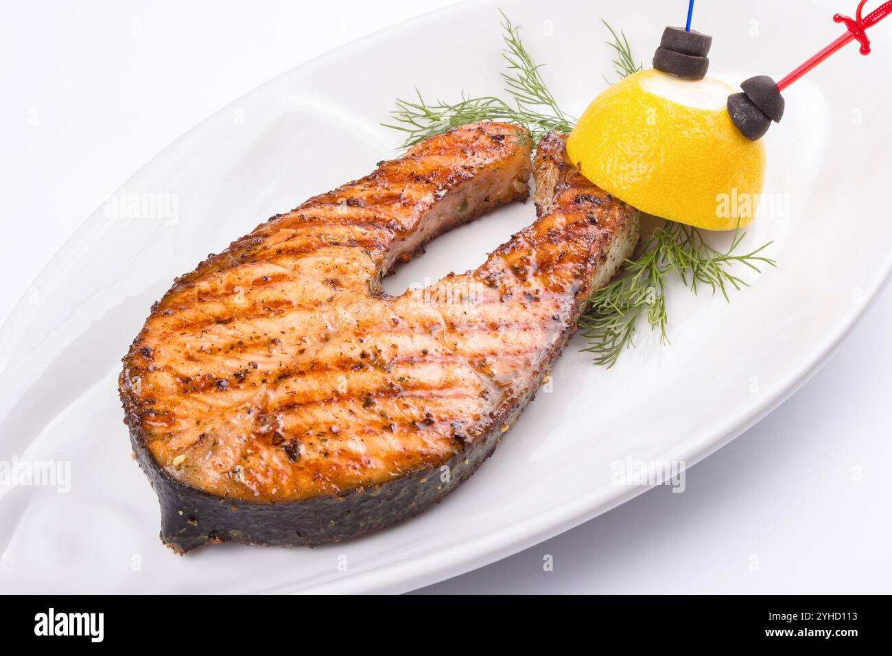 grilled fish steak on the white plate decorated with lemon. side view. appetizing juicy salmon Stock Photo