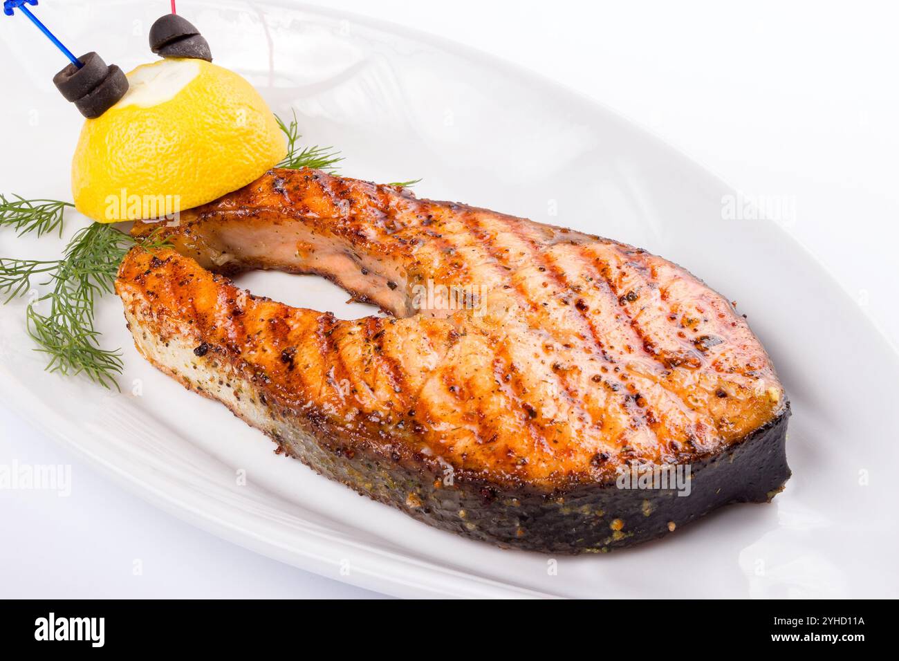 grilled fish steak on the white plate decorated with lemon Stock Photo