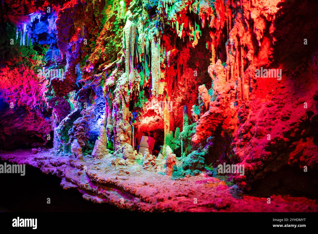 Shenandoah Caverns Stalactites Stalagmites Quicksburg Virginia // QUICKSBURG, Virginia — Colored lighting illuminates the natural formations within Shenandoah Caverns, enhancing the visual drama of the underground limestone features. The strategic placement of lights throughout the cave system highlights the textures and dimensions of stalactites, stalagmites, and flowstone formations, creating an engaging atmosphere for visitors exploring the caverns. Stock Photo