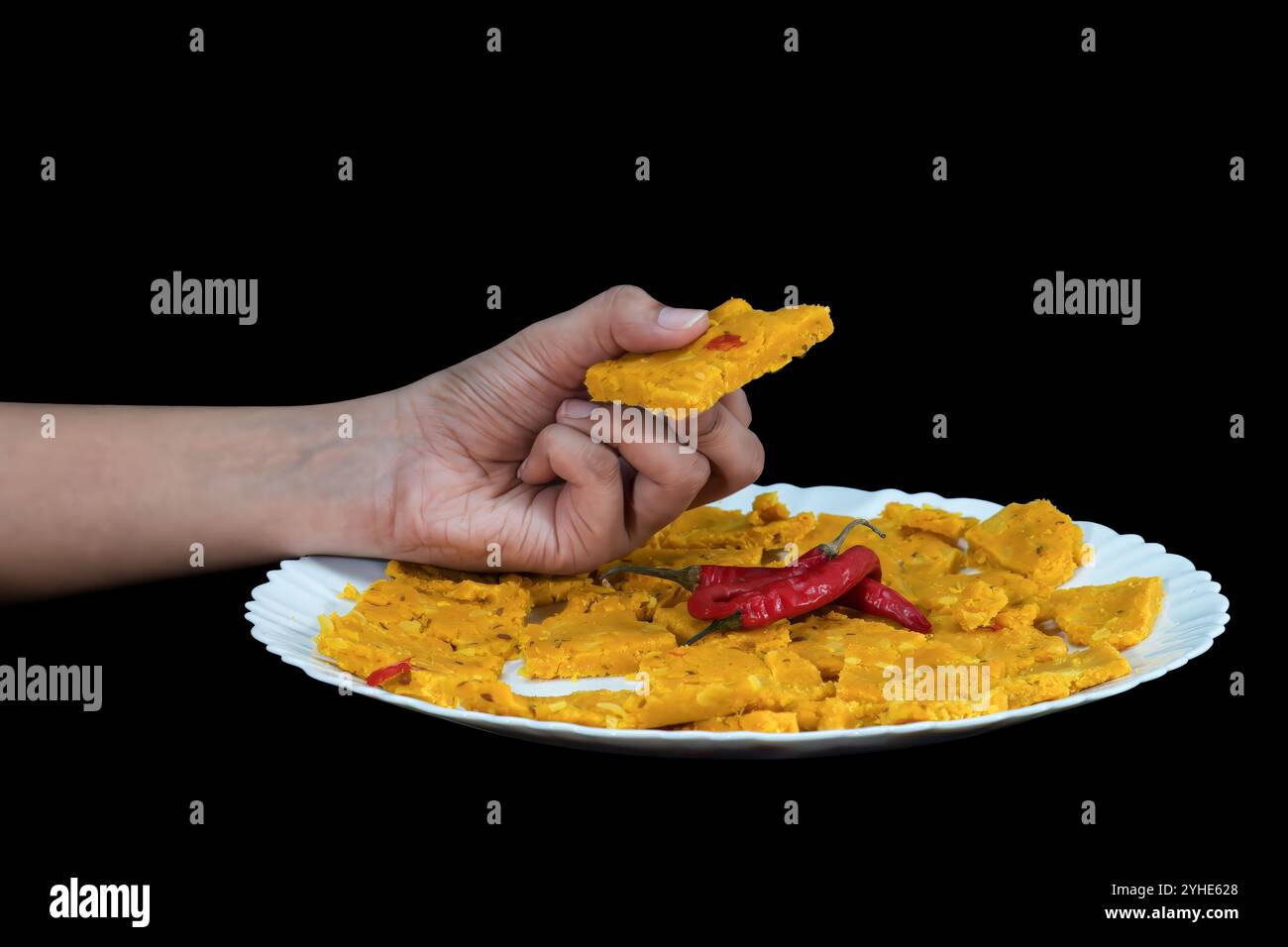 Girl Holding Spicy Dhokli In Hand Gujarati Kathiyawadi, Isolated Black Background, Selective Focus Stock Photo