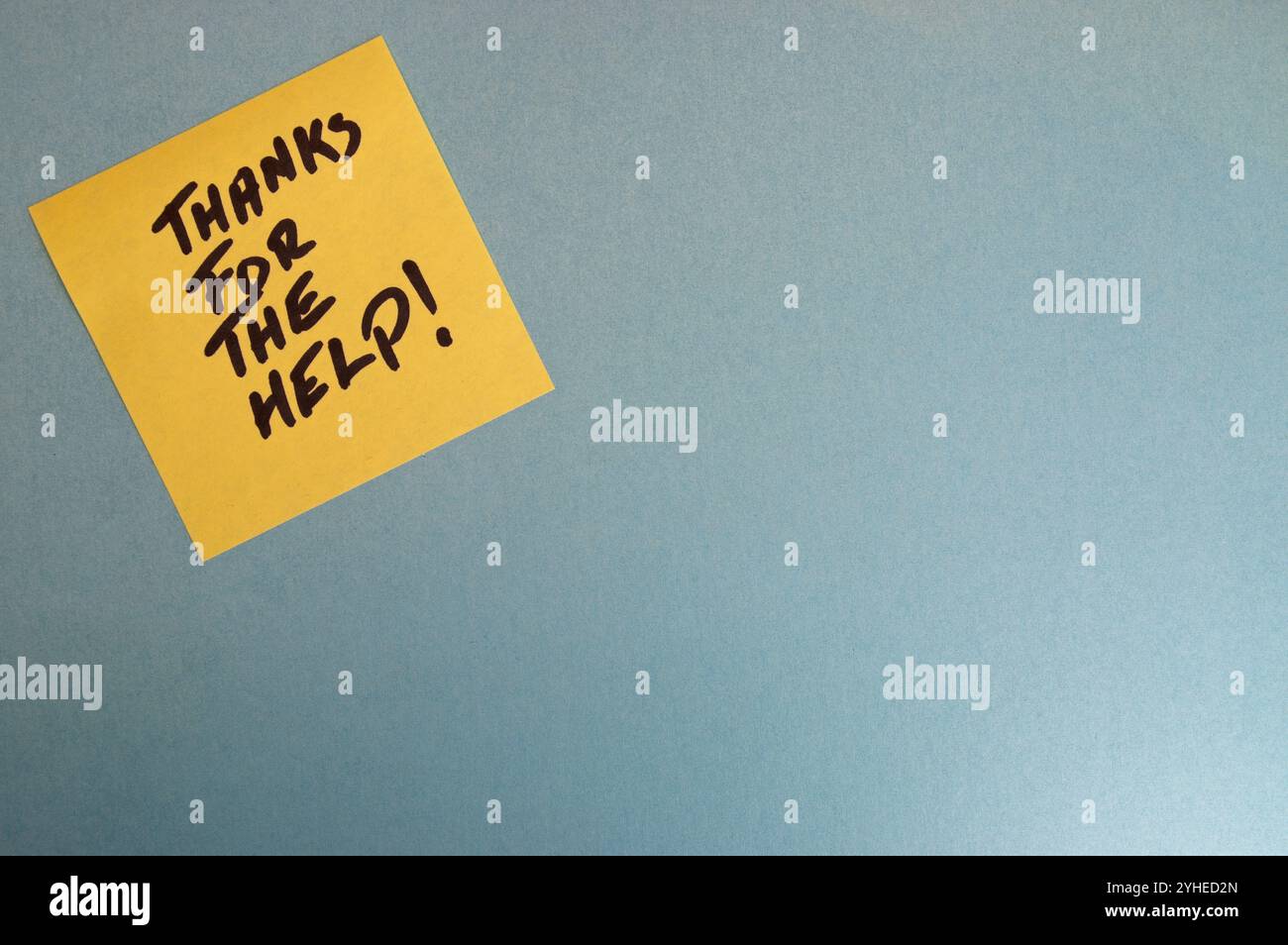 Yellow sticky note on a blue background with handwritten text that reads Thanks for the help, in black marker Stock Photo