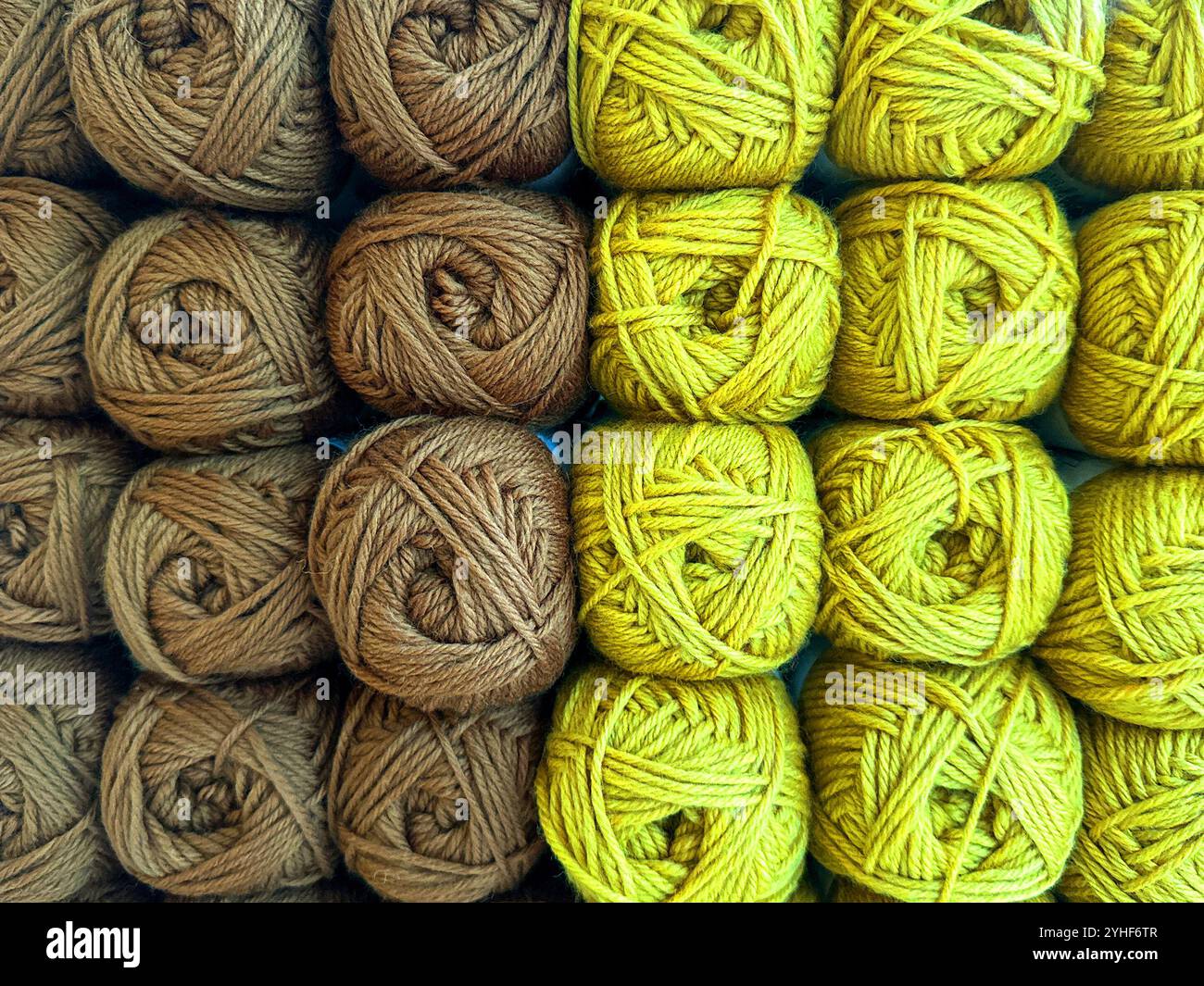 Close up view of balls of brown and lime green wool on display in a knitting shop.. - Smartphone Captured Stock Image