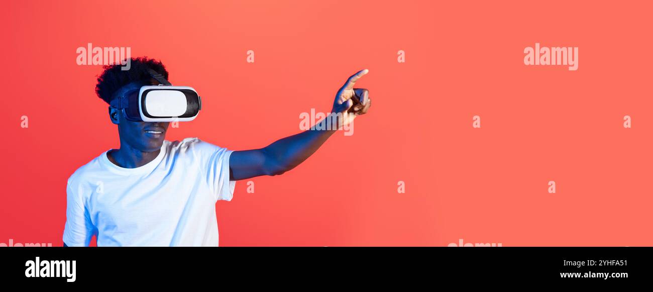 Young man interacts with virtual reality headset in a vibrant studio setting Stock Photo