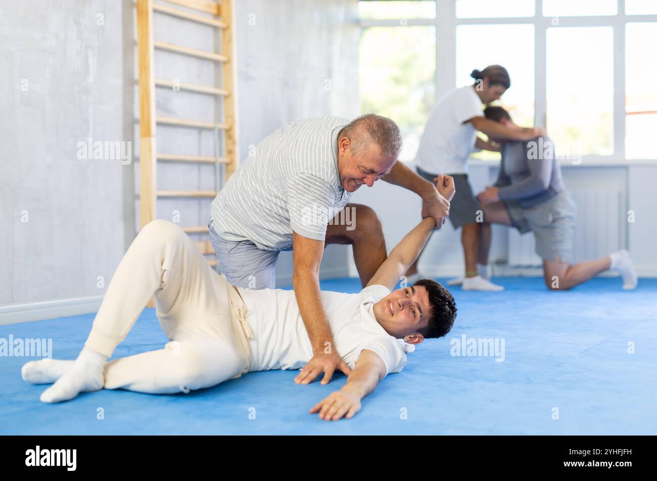 Two men at group judo lesson practicing techniques in sparring, in ...