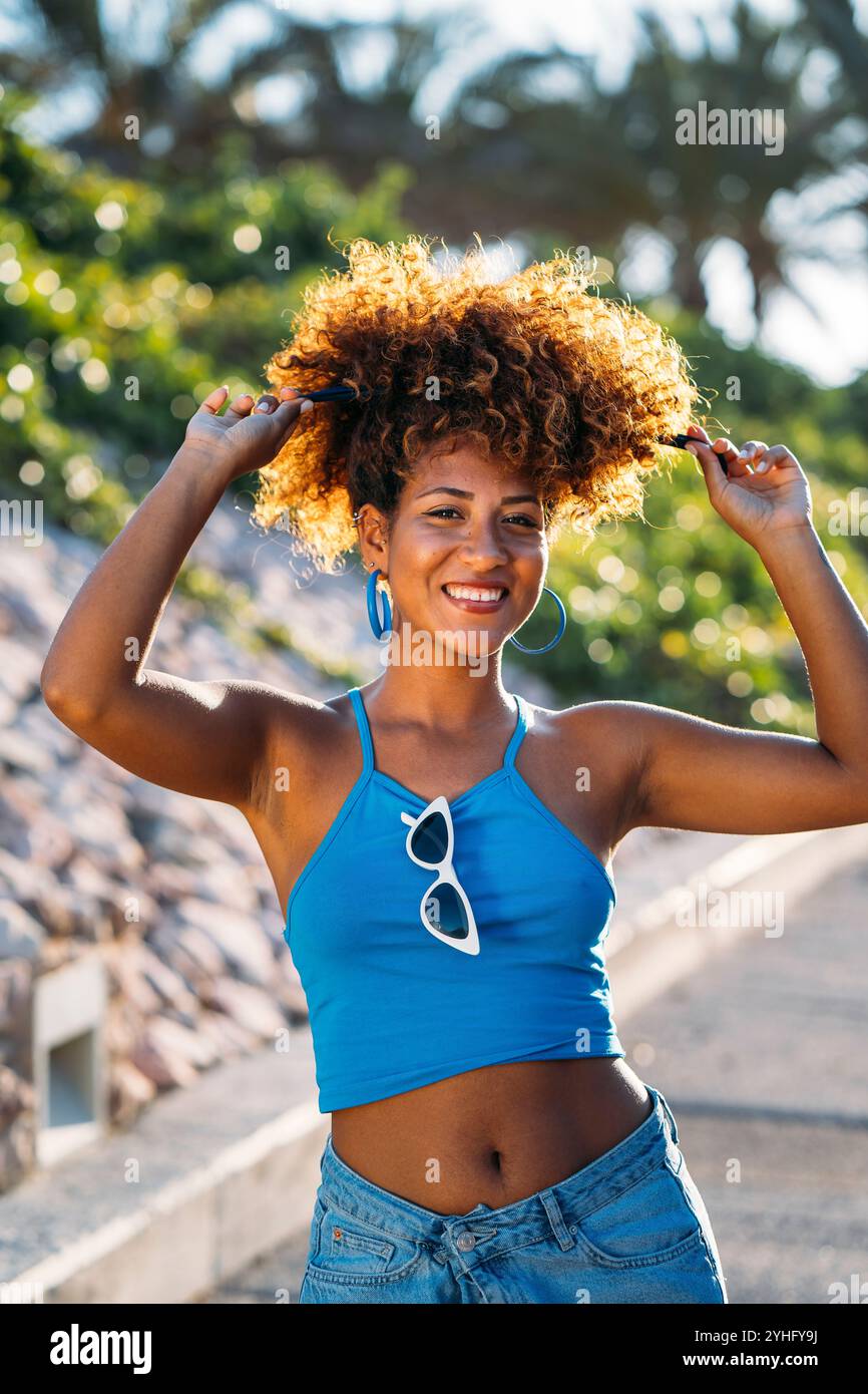 Beautiful smiling black woman playing with her afro hair in the street ...