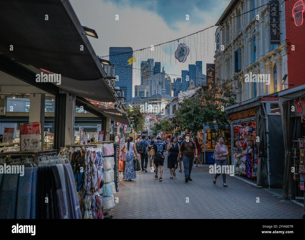A general view of Chinatown evening market area looking towards the city skyscrapers in the distance with people exploring the area in the foreground. Stock Photo
