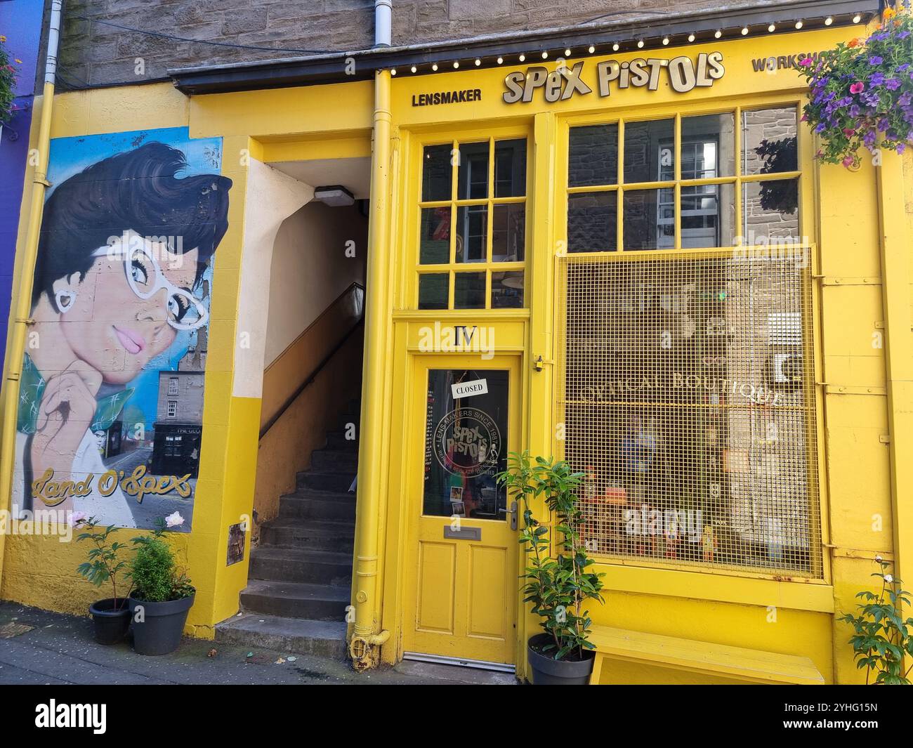Bright yellow facade of Spex Pistols, optical boutique, lens maker, wall painting with text Land O'Spex in Dundee, Scotland, UK, United Kingdom - Smartphone Captured Stock Image