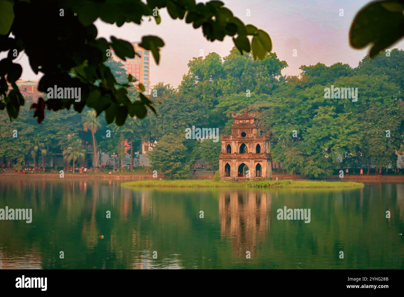 The Turtle Tower at Hoan Kiem Lake in Hanoi, Vietnam, captured during a tranquil moment with the morning light reflecting off the water. Stock Photo