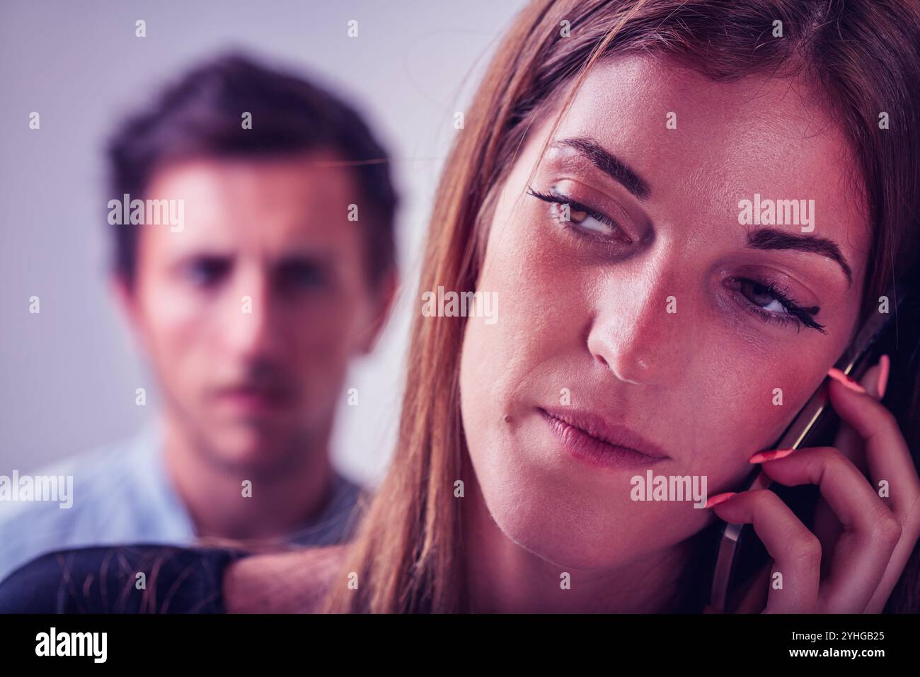 woman, deep in conversation, is observed by a man with a cautious look ...