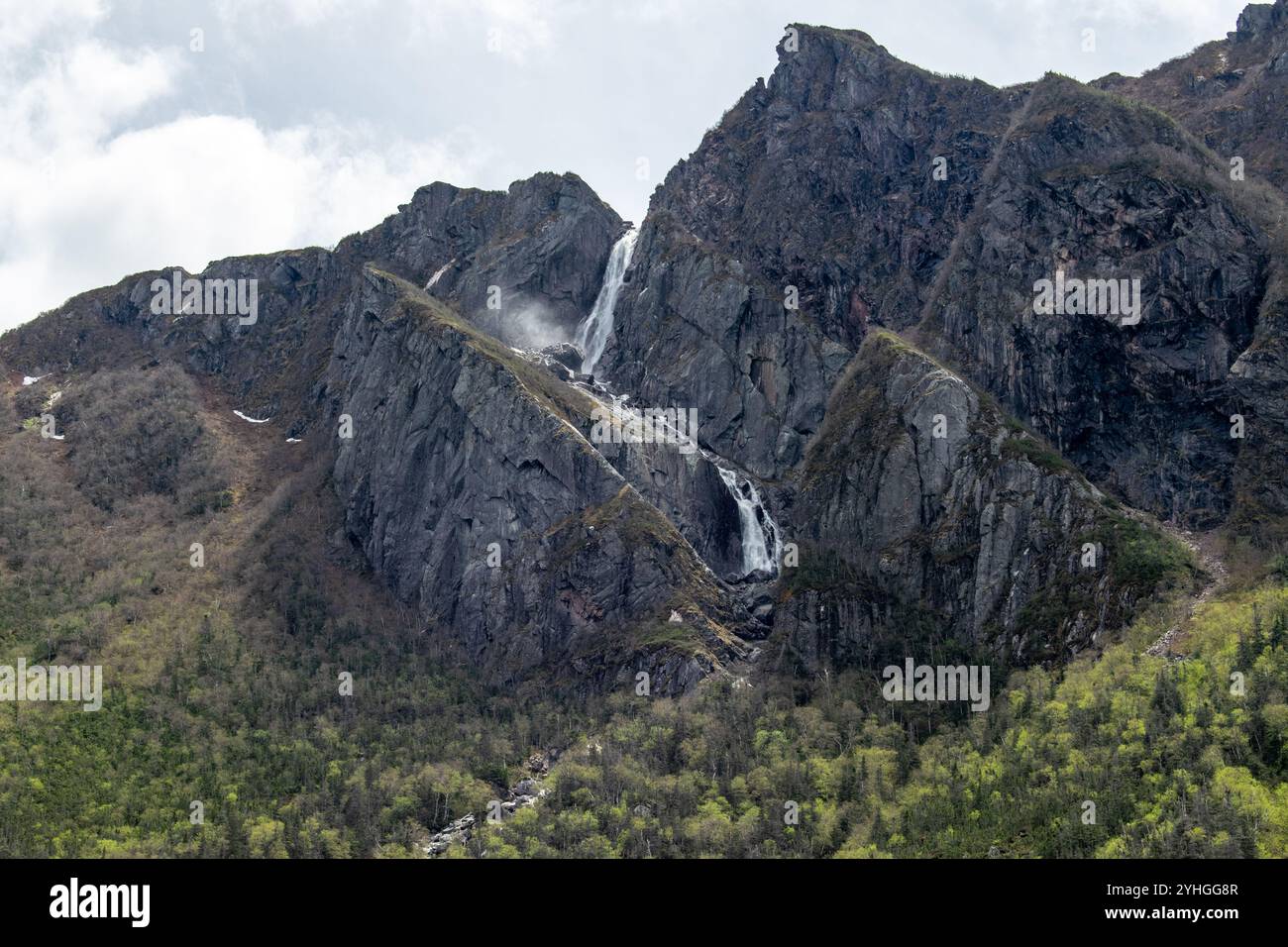 At the top of a towering cliff in Gros Morne, a small waterfall ...