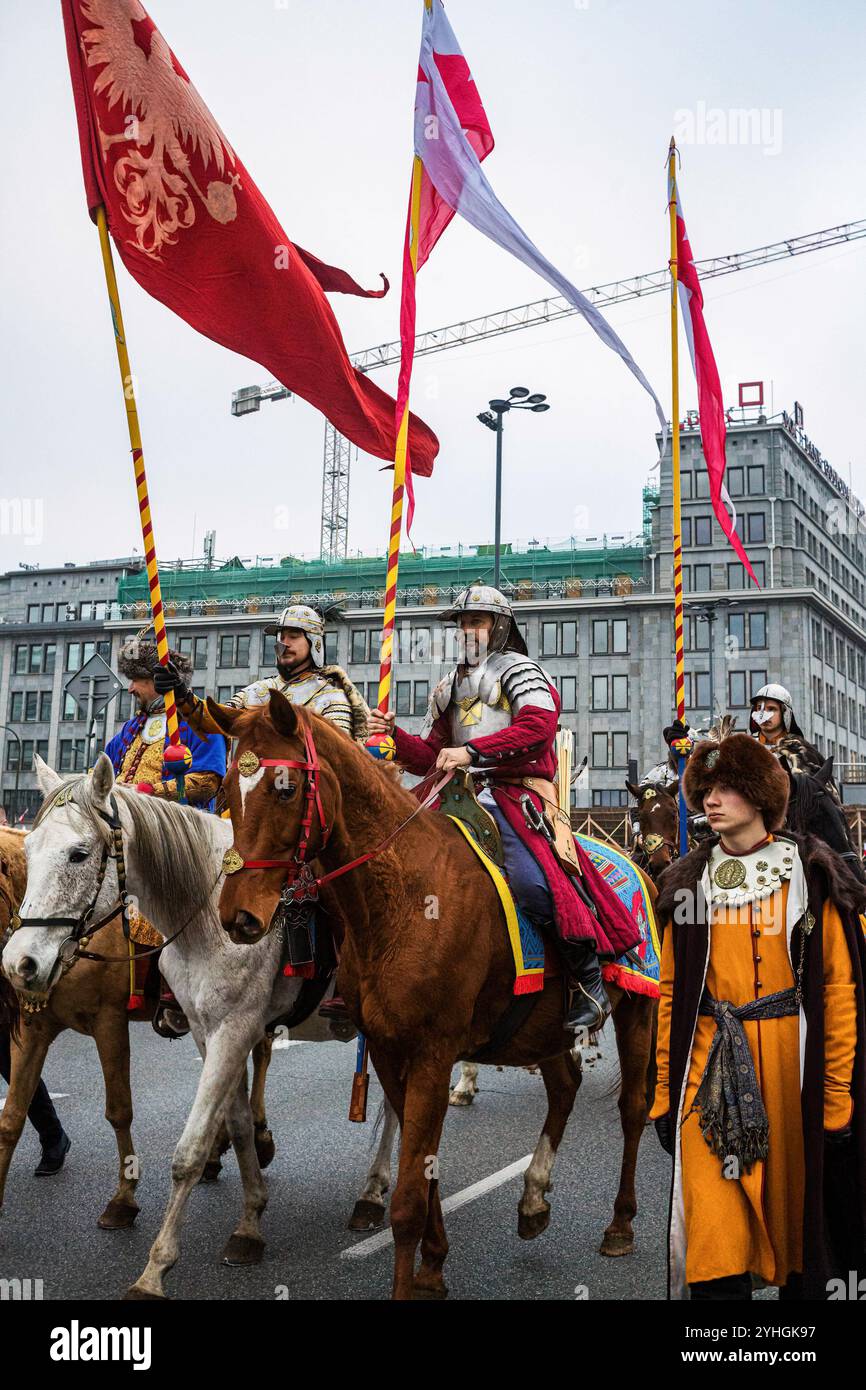 Participants dressed in period outfits on horseback parade as part of the march. Polish citizens from all over the country march through the streets of Warsaw to celebrate Independence Day. The event gathers tens of thousands of participants, with patriotic Poles gathering to celebrate. Many families bringing their children. The march has religious undertones with much religious symbolism seen in flags and banners. Many far-right and fascist organisations also march. The march itself was initiated by far-right groups and has been marred by controversy as it is seen by many as promoting fascism Stock Photo