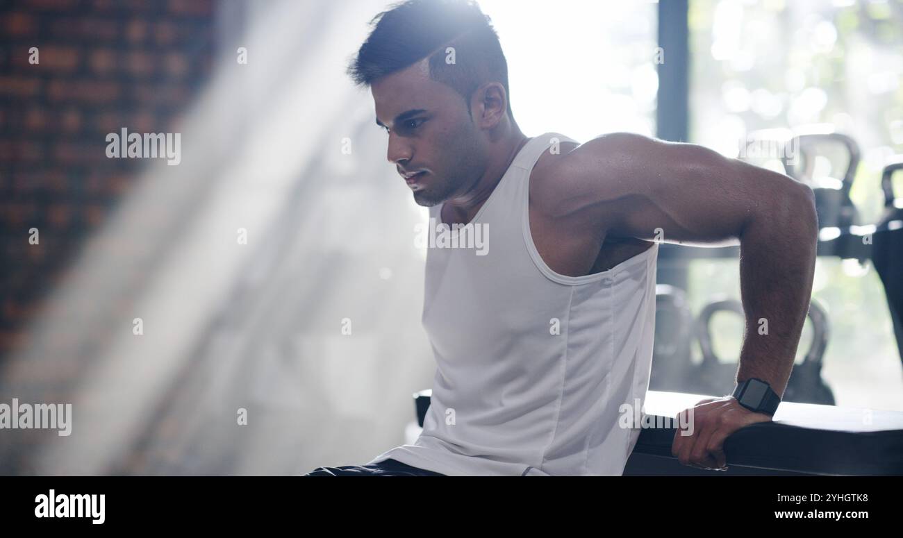 Fitness, man and triceps dips in gym for muscle, bodyweight exercise and strength training for body health. Strong, bodybuilder and workout arms for Stock Photo