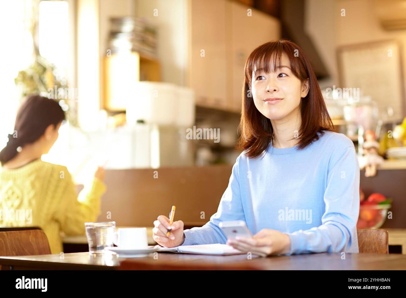 Woman checking her schedule book while looking at her mobile phone in a café Stock Photo