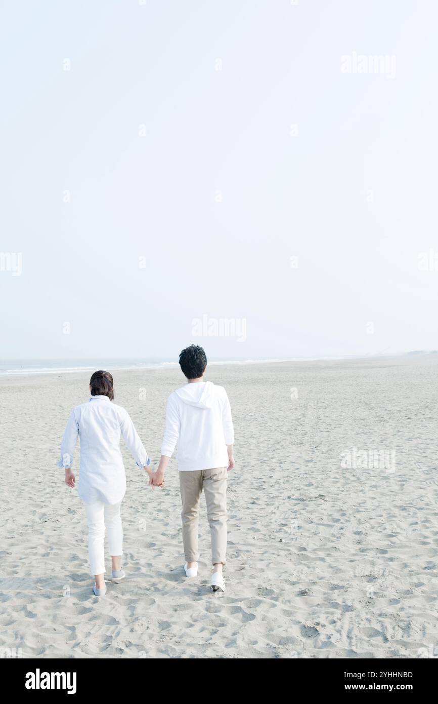 Back view of couple on seaside walking hand in hand Stock Photo - Alamy