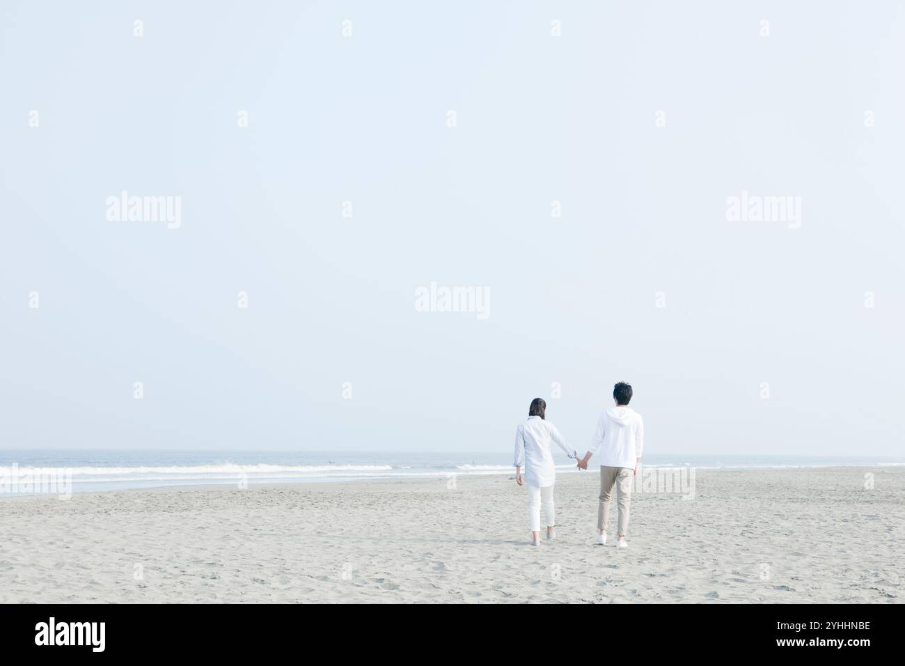 Back view of couple on seaside walking hand in hand Stock Photo - Alamy