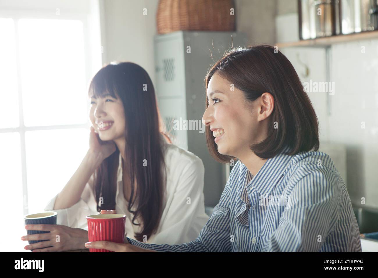 Two women in their 20s relaxing in the kitchen Stock Photo - Alamy